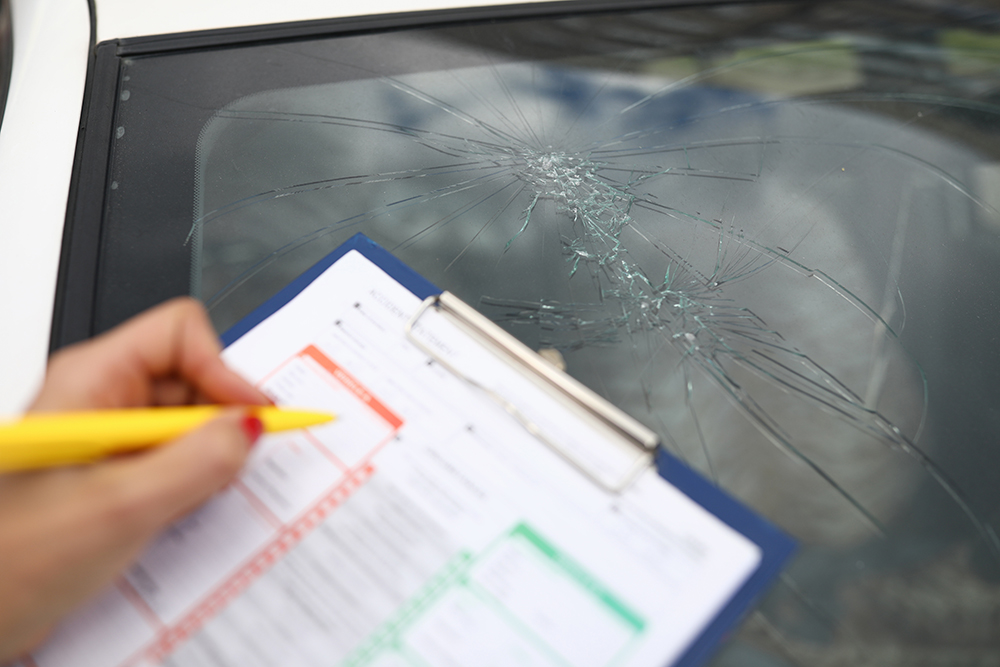 An agent draws up documents for broken windshield in car.